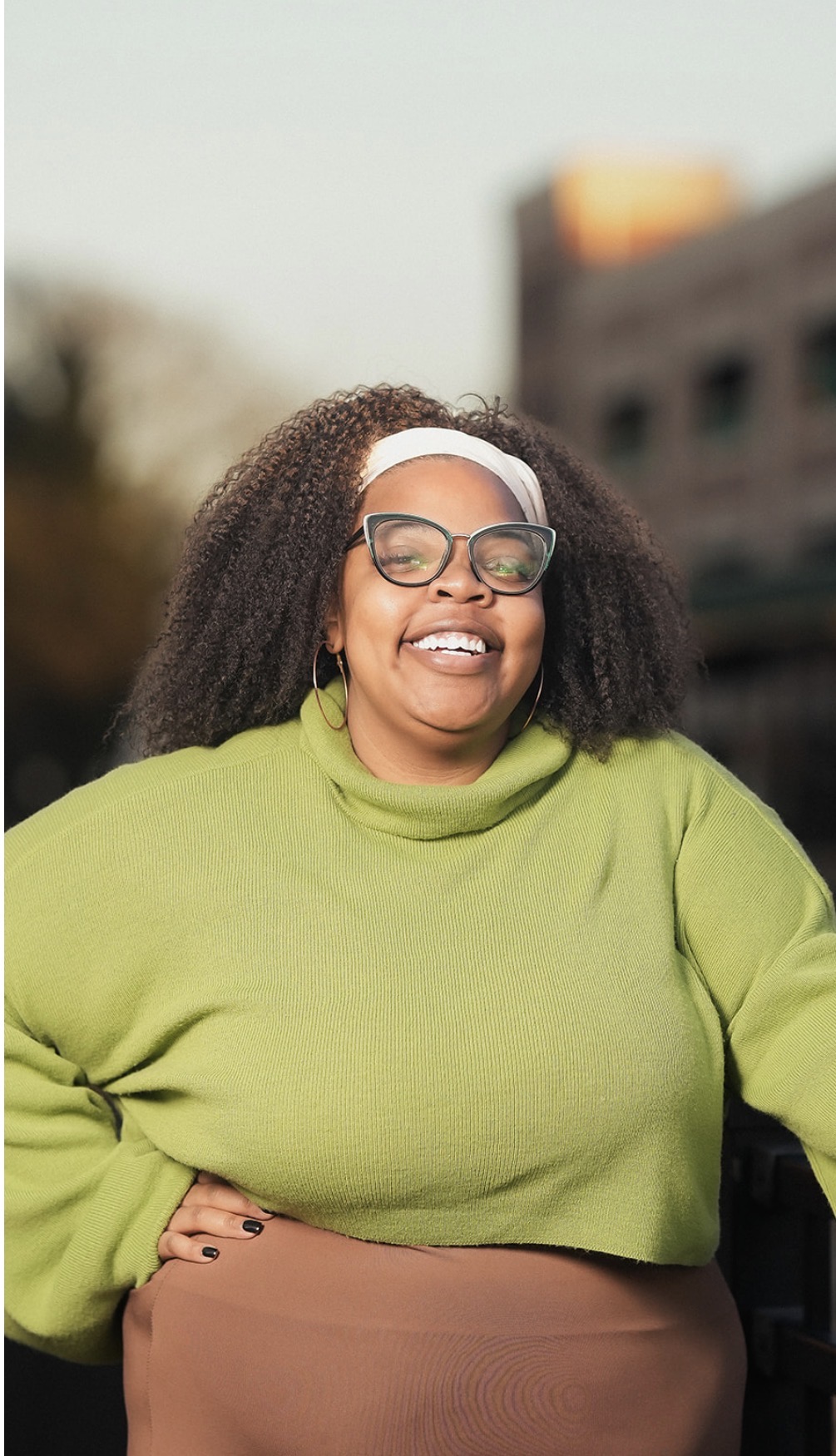 Shantè Davis laughing outdoors in a green sweater
